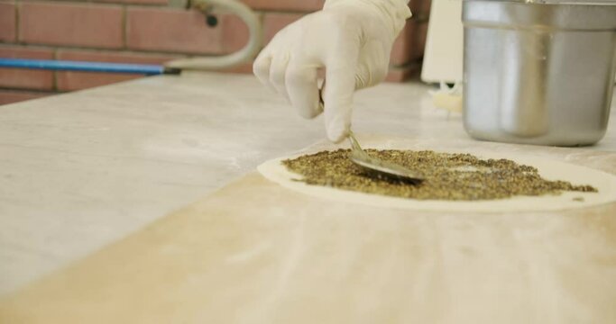 Spreading za'atar or zaatar on dough in a traditional kitchen