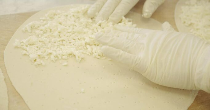 Spreading cheese on manakish or flat dough bread like pizza