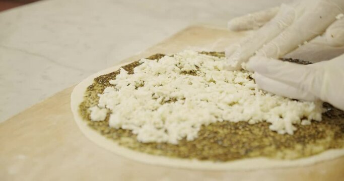 Adding and spreading cheese on Za'atar manakish