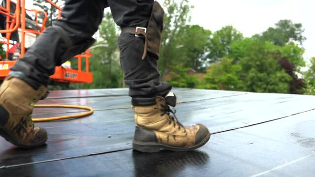 Man's Feet In Safety Boots Walking On Flat Roof At The Construction Site. close up, cropped shot
