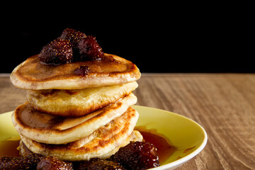 Homemade pancakes with strawberry jam and berries on a wooden board