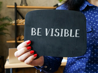 Business concept about BE VISIBLE with sign on the sheet.