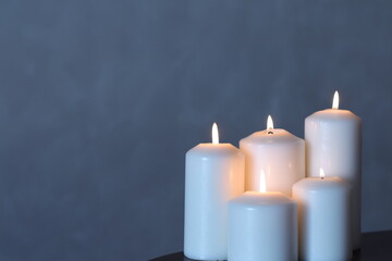 A group of white candles arranged in a tiered arrangement on a plain background.