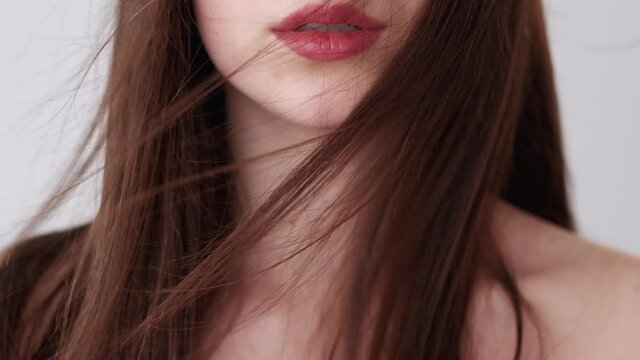 Hair care. Keratin treatment. Beauty fashion. Professional cosmetics. Brunette pretty woman with full sensual red lips isolated on light.