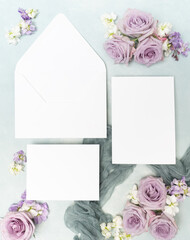 Obraz na płótnie Canvas Beautiful violet fresh roses and blank wedding stationery flat lay
