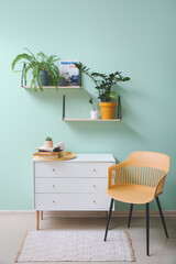 Interior of modern room with chest of drawers, chair and shelves