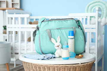 Bottle of milk for baby and bag on table in room