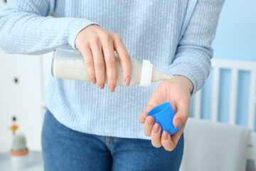 Woman checking temperature of baby formula, closeup