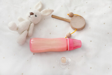 Bottle of milk for baby with toys on bed