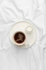 Tray with cup of coffee and milk on bed