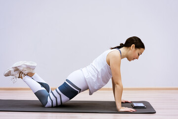 A woman goes in for sports watching an online video from a tablet. Fitness class concept ss workout...