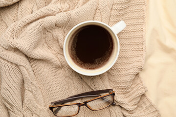 Cup of coffee and glasses on bed
