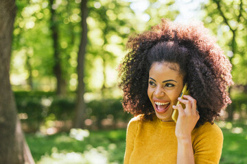 Pretty afro woman talking on the mobile happy, in a garden.