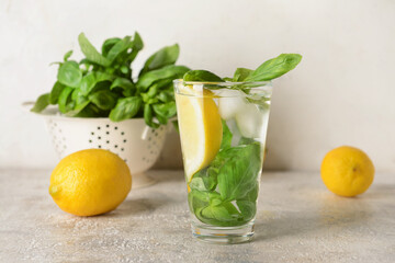 Glass of lemonade with basil on light background