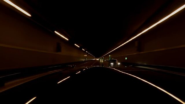 Rear view from a car by night driving fast through the underground and tunnels with other cars as a hyper lapse