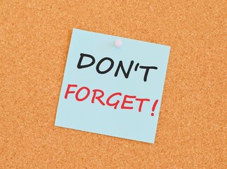 Note with don't forget. Blank light blue sticky note with don't forget pined on a cork bulletin board.
