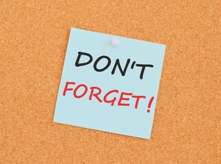 Note with don't forget. Blank light blue sticky note with don't forget pined on a cork bulletin...