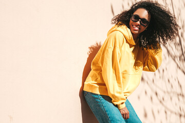 Beautiful black woman with afro curls hairstyle.Smiling hipster model in yellow hoodie. Sexy...