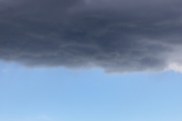 a blue sky with dark storm clouds. Rain clouds are gathering and a thunderstorm is coming. 
