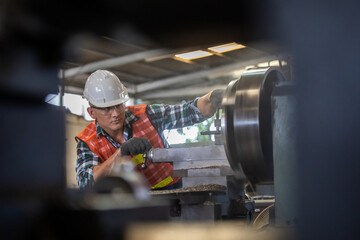 worker is working on a lathe machine in a factory. Turner worker manages the metalworking process of mechanical cutting on a lathe