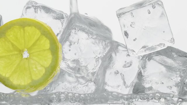Einschenken von frischem Mineralwasserglas gef&uuml;llt  mit Zitronenscheibe und Eisw&uuml;rfel