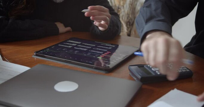Male and female hands analyzing financial series and taking notes, close up