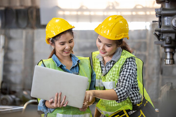 Asian engineering and worker woman in safety hard hat and reflective cloth using lathe machine inside the factory. A portrait of an industrial woman engineer with laptop in a factory,