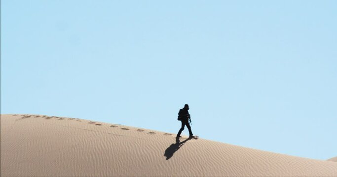 Beautiful cinematic silhouette of soldier walking through arid desert landscape, America