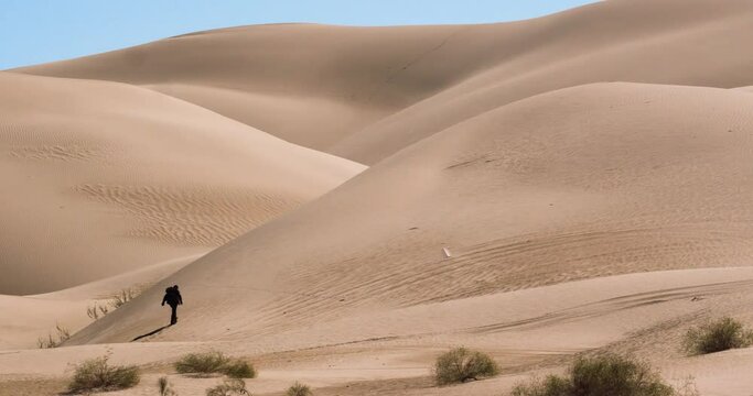 Wide shot of man wandering lost over sand dunes in Arizona desert, America