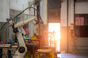 industrial machine and factory robot arm. robotic machine work together inside industrial building. The mechanical arm performs welds on metal components