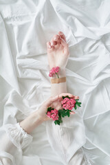 Creative spring floral aesthetics concept. Girls hands holding tender small pink daisy flowers, one of them applied to hand with patch on white background, top view with copy space. High quality photo