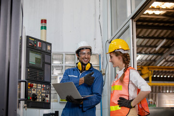 portrait of an industrial man and woman engineer with tablet in a factory. Factory worker is programming a CNC milling machine with a tablet computer