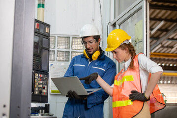 portrait of an industrial man and woman engineer with tablet in a factory. Factory worker is programming a CNC milling machine with a tablet computer