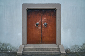 A vintage red Chinese door with metal doorknobs.