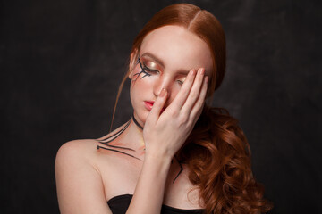 Redhead woman with closed eyes covering her hand her face on black background, mental problem...