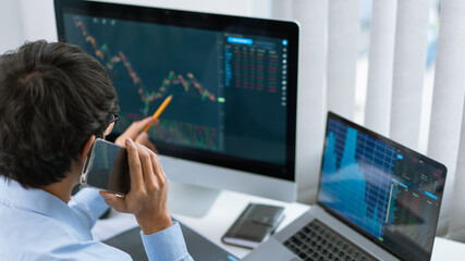 Financial concept a male trader speaking on his mobile phone about the trend of the present stock.