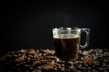 a cup of coffee on a black background with grains and badyan. High quality photo
