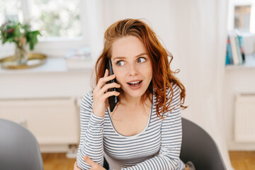 Young woman listening in excited fascination to a call
