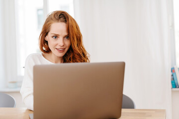 Young redhead woman staring in astonishment at a laptop