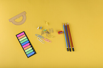 office supplies on a yellow background. Paper clips, buttons, notepads, pencils. Study, office