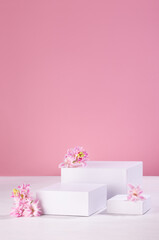 Spring gentle mockup with three white podiums for showing cosmetic product with hyacinth flowers and soft light pastel pink background, vertical.