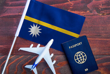 Flag of Nauru with passport and toy airplane on wooden background. Flight travel concept
