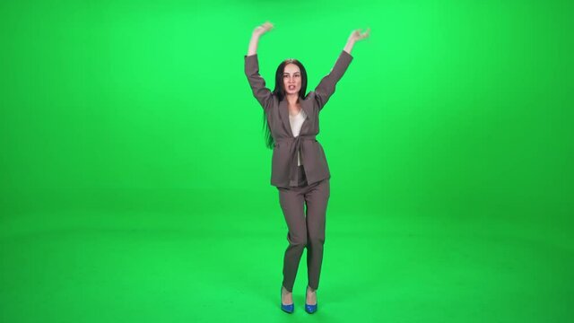 Caucasian cheerful female dancing at a music concert, dance and swing their arms on a green background, chromakey template.