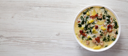 Homemade Zuppa Toscana with Kale and Bread in a white bowl, top view. Flat lay, overhead, from above. Copy space.