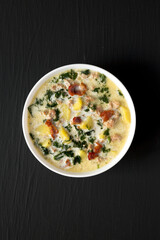 Homemade Zuppa Toscana with Kale and Bread in a white bowl on a black background, top view. Overhead, from above, flat lay.
