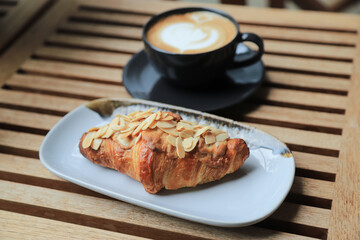Selective focus on almond crossiant with hot coffee on background in home morning eating