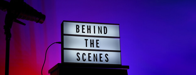 Behind the scenes letterboard text on Lightbox or Cinema Light box. Movie clapperboard megaphone and director chair beside. Background LED color change loop. static camera in video production studio.