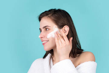 Beauty portrait of beautiful female model apply a cleansing mask on face. Woman apply facial cream lifting nourishing day creme on soft hydrated moisturized skin.