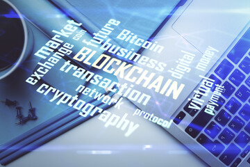 Blockchain theme hologram drawings over computer on the desktop background. Top view. Multi...