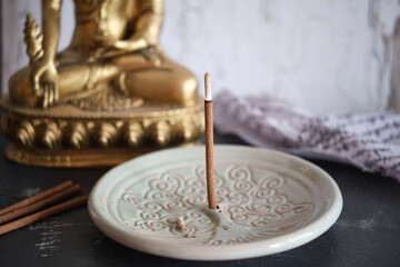 Tibetische Räucherstäbchen auf rundem Halter Yggdrasil mit goldenem Buddha (Close-up)
